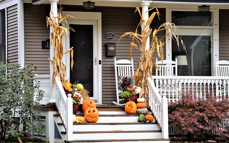 fall and halloween decor on the front porch of suburban home