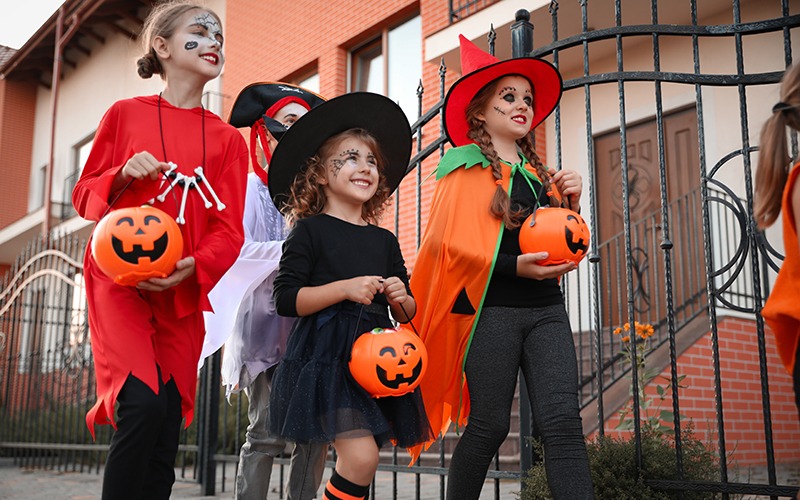 Cute little kids wearing Halloween costumes going trick-or-treating outdoors