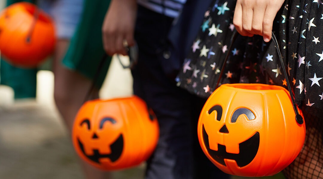 close up of trick or treaters holding pumpkin buckets