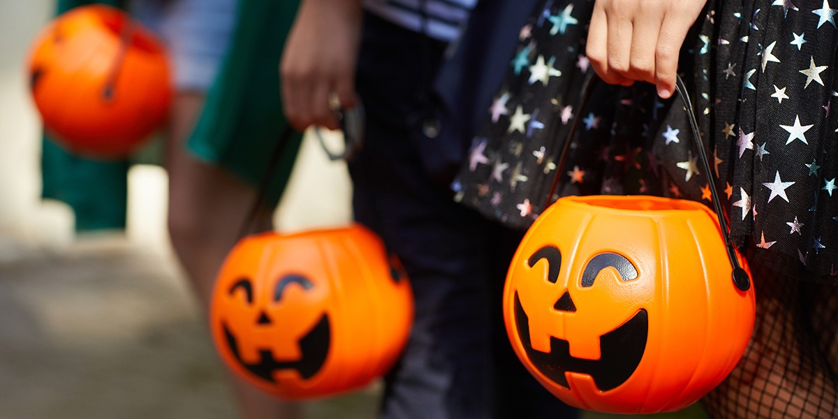 close up of trick or treaters holding pumpkin buckets
